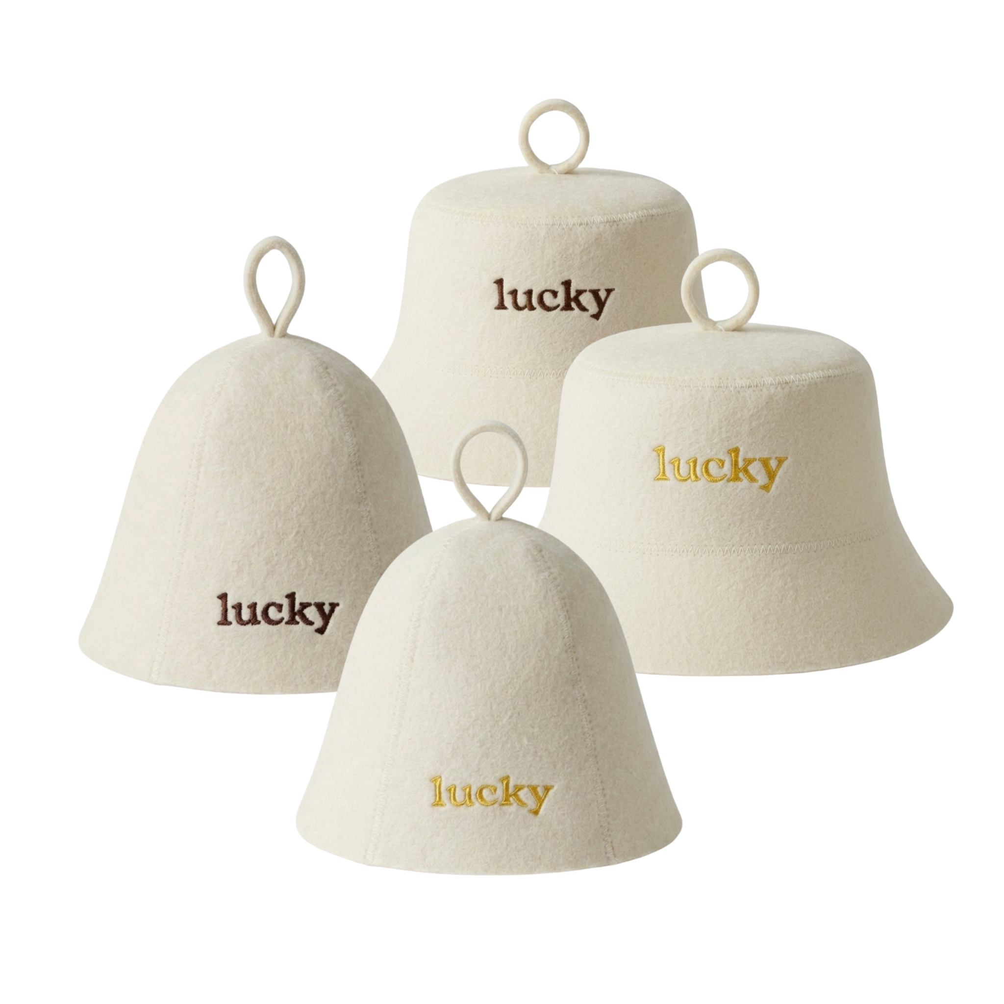 Four cream-colored felt bell-shaped sauna hats with hanging loops, each embroidered with the word 'lucky' in different font colors: two in dark brown, two in gold.